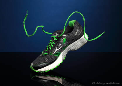 Running shoe in motion with floating laces on a shiny black surface with blue background